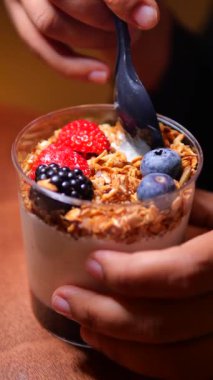 Bir insan yoğurt yiyor tahıl gevreği ve taze böğürtlen ile karıştırılmış..