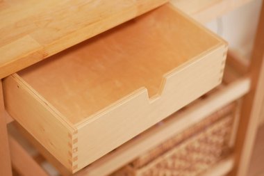 Mutfak alanındaki bir raftan ahşap bir çekmece çıkarılıyor..