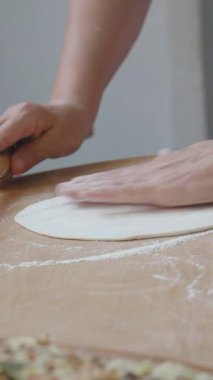 Elleri hamuru un kaplı bir masaya iğneyle yuvarlıyor..