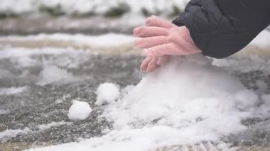 Hands are forming a snowball on a cold winter day outside.