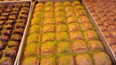 İnsanlar yoğun bir şekerci dükkanından baklava alıp tadıyorlar..