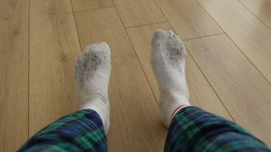 Kirli çoraplar ve ekose pantolonla yerde oturan kişi.