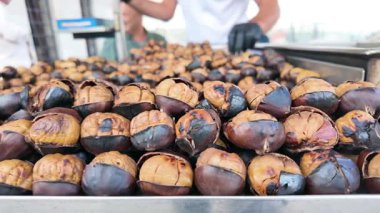 İnsanlar sonbaharda kalabalık bir cadde pazarında ızgara kestane sever..