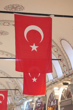 Bir markette tavandan sarkan beyaz sembollü iki kırmızı bayrak..