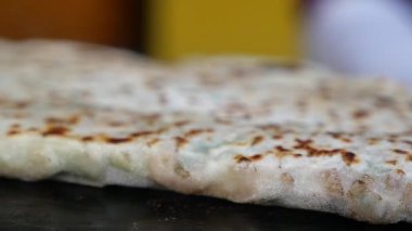 Düz ekmek sıcak bir yüzeyde pişirirken, aşçılar onun etrafında çalışır..