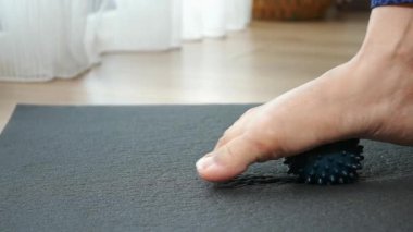 Bir insan evdeki bir paspasın üzerinde ayak masajı topunu kullanır..