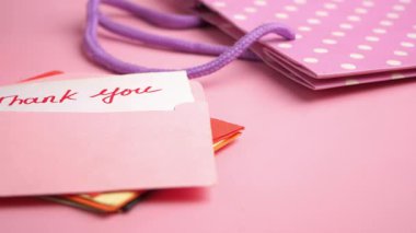 Resim pembe bir yüzey üzerinde hediye kartları ve bir teşekkür notu gösteriyor..