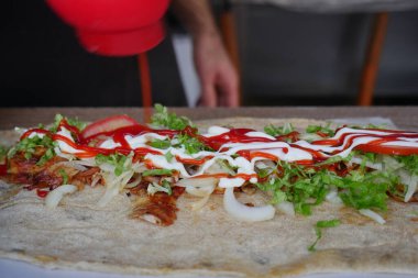 Bir aşçı yemek büfesine sos ve malzemeler ekler..