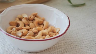 Kaju fıstıkları beyaz bir kâseye yerleştirilir. Tarafsız bir arka planı olan bir masanın üzerinde..