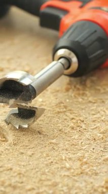 Bir tezgah üzerindeki odun talaşlarına yerleştirilmiş bir matkap ucu görülüyor..