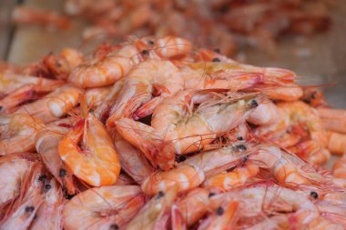 İnsanlar büyük bir taze karides yığınının etrafında toplanıp pazarda satıyorlar..