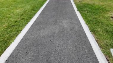 Parktaki bir patika düz yüzeyi ve yeşil kenarları gösterir.