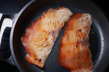 Sobanın tepesinde tavada somon balığı pişiriyorum.,