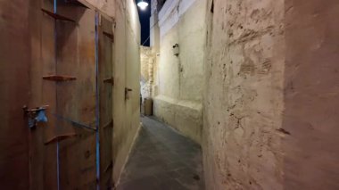 Taş duvarlar ve ahşap kapılarla dar bir sokakta yürüyorum..