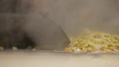 Bir aşçı, mutfak tezgahında lahana ve tavuk doğrar..