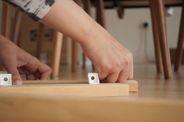 Bir insan bir odada yere mobilya yapmak için el aletleri kullanır..