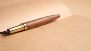 Bir kalem boş kahverengi kağıda uzanır not veya fikir yazmaya hazırdır.