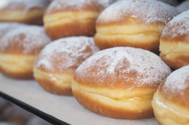 Pastanede üzerinde pudra şekeri olan çeşitli çörekler sergileniyor..