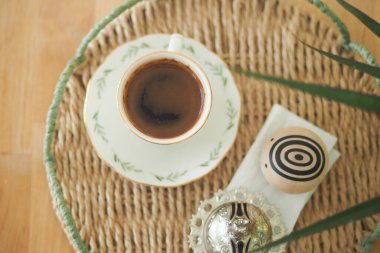 Bir kahve fincanı, yanındaki diğer eşyalarla birlikte yuvarlak bir tepside oturur..