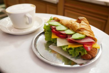 Sebzeli sandviç ve masada bir fincan kahve..