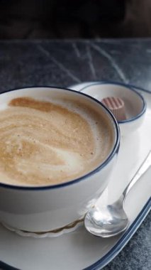 Kafedeki masada tatlı ile kahveyi yudumlayan biri..