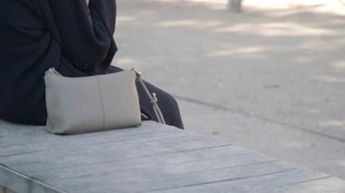 Güneşli bir günde parkta bir bankta sessizce oturan kişi.