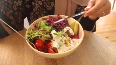 Bir insan gün boyunca rahat bir kafede renkli bir salata kasesi yer..