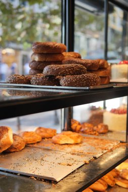 Ekmek ve hamur işleri bir fırının raflarında düzenlenir. İnsanlar dışarıda yürüyor..