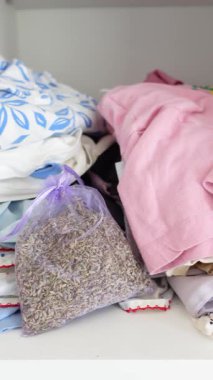 Raftaki eşyalar arasında kumaşlar ve bir torba lavanta var..