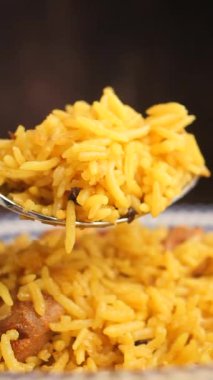 Birisi tavuklu baharatlı sarı pilav hazırlıyor..