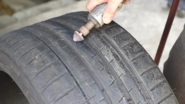 Gündüz vakti dışarıda bir aletle lastik izi üzerinde çalışan bir kişi var..