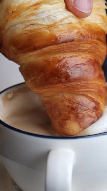 Yerel bir kafede sıcak bir hamur işi bir fincan kahveye batırılır..