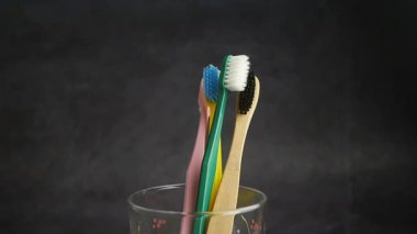 Çeşitli kıllara sahip dört diş fırçası cam bir kabın içinde..