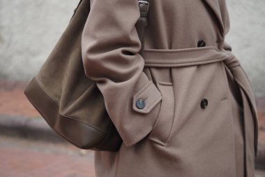 Bir insan elini ceketinin cebine sokar ve bir çanta tutar..