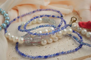 Çeşitli boncuk ve kolyeler kumaşın yanında düz bir yüzeye yerleştirilir..