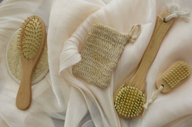 Çeşitli ahşap fırçalar ve kumaşın üzerine desenli bir kese konur..