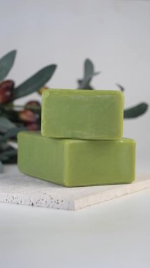 Beyaz arkaplanda yeşil sabun ve zeytin.