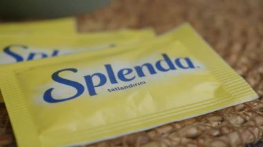 Bir insan içeceğe eklemek için bir paket tatlandırıcı açar..