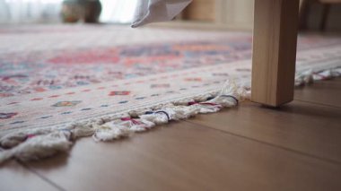 A chair leg rests on the edge of a rug in a home setting.
