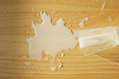 Bir fincan düşer ve süt ahşap yüzeye yayılır..