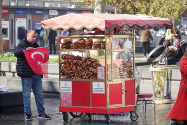 Bir adam elinde Türk bayrağı varken el arabasıyla ekmek satıyor..