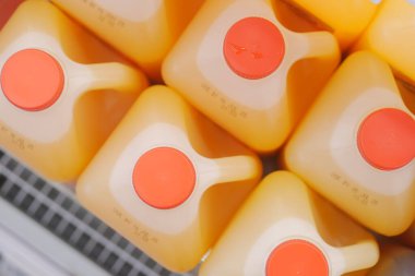 Turuncu kapaklı sarı kaplar bir dükkanda düz bir yüzeye oturur..