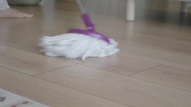 A person is cleaning a wood floor using a mop in their home.
