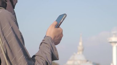 Şehirde dışarıda dikilen biri akıllı telefonunu kontrol eder..