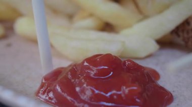 İnsanlar yerel bir yerde patates kızartmasını kalın ketçapa batırıyorlar..