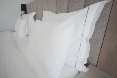 Beyaz yastıklar düzgünce düzenlenmiş bir otel yatağında dinleniyor..