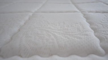 Exploring the texture and pattern of a white mattress fabric closely.
