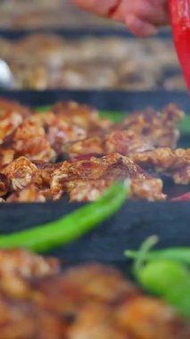 İnsanlar dışarıdaki ızgarada tavuk ve yeşil sebze pişiriyor..