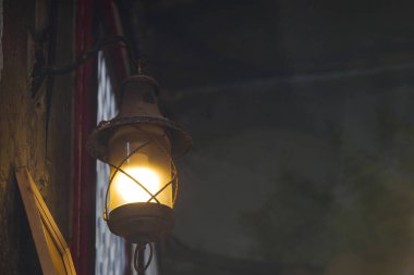 Ilık ışığı olan bir fener loş bir uzayda asılı duruyor. Sıcaklık katıyor..