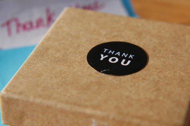 Üzerinde teşekkür etiketi olan küçük kahverengi bir kutu masada oturuyor..